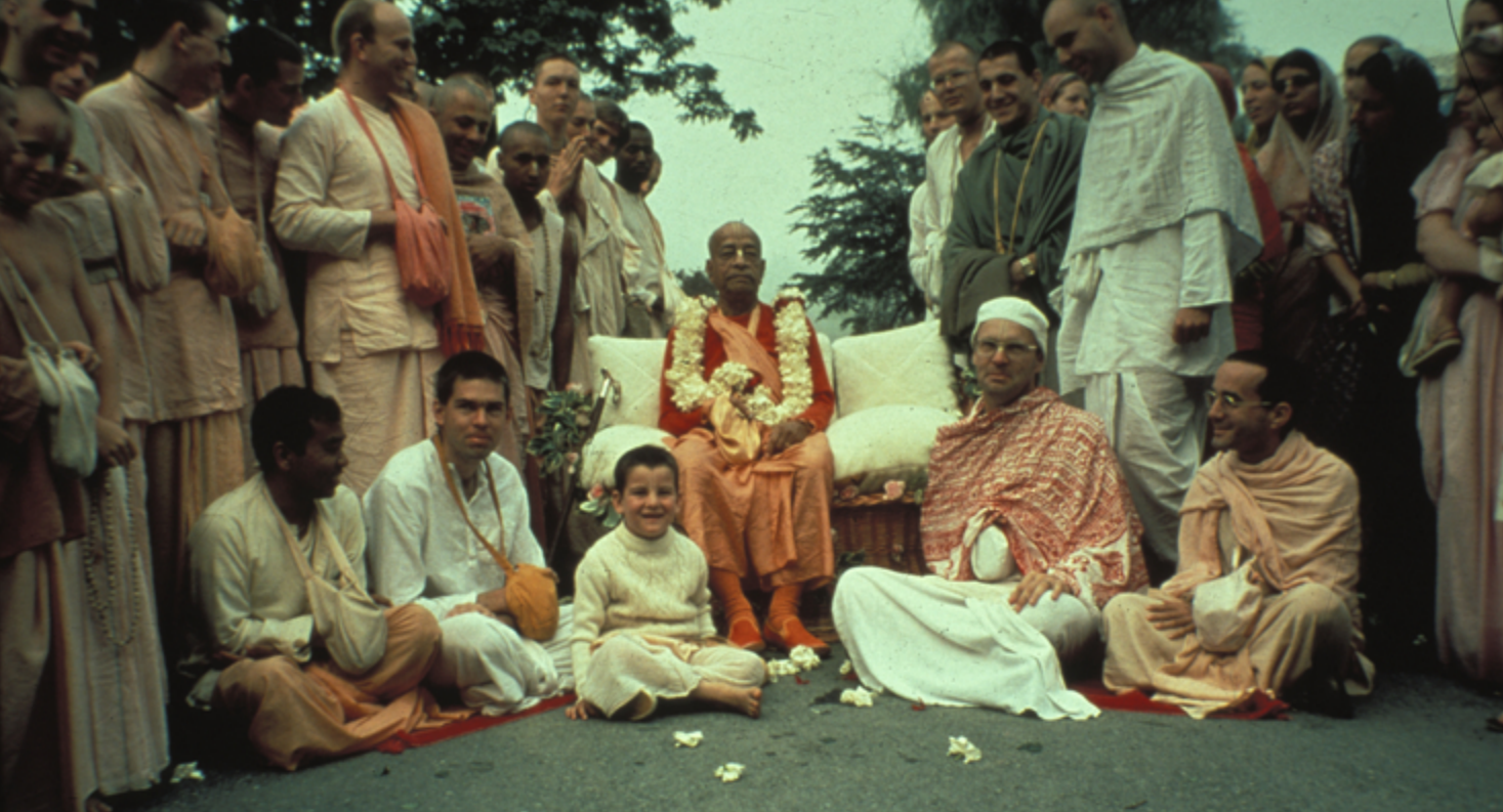 Prabhupada seated with founding members of the Bhaktivedanta Institute and a large group of devotees